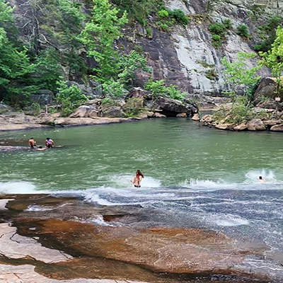 woman sliding down rock into swimming hole