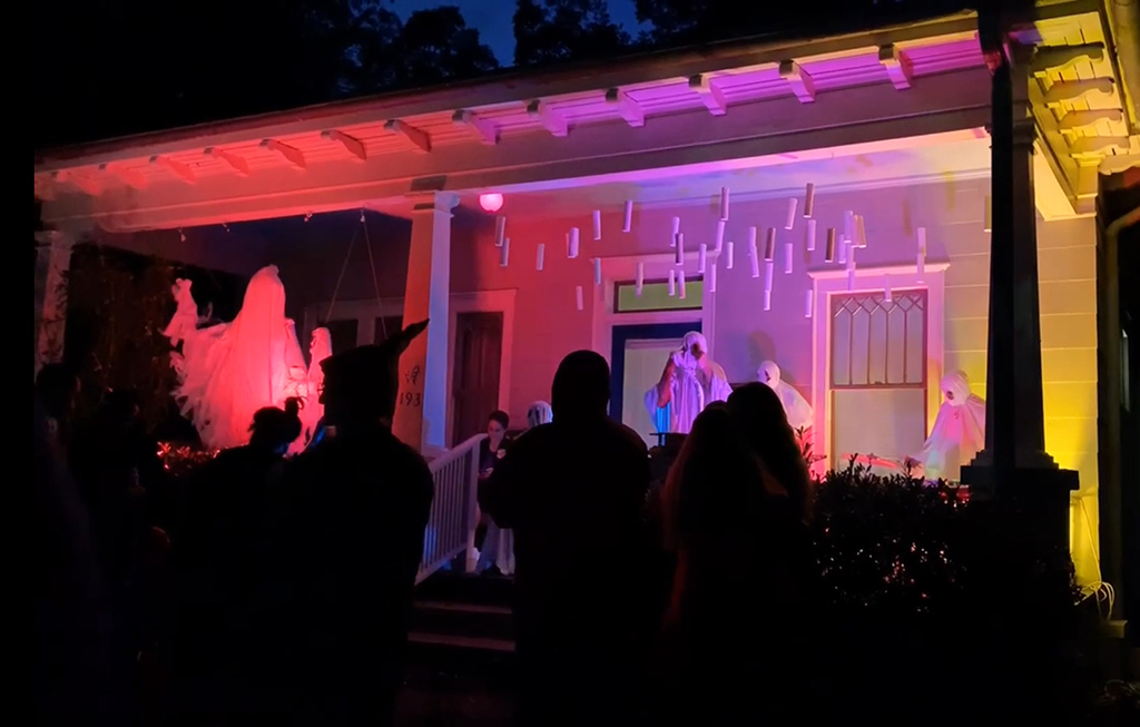 a band dressed up as ghosts on a lit up porch at night