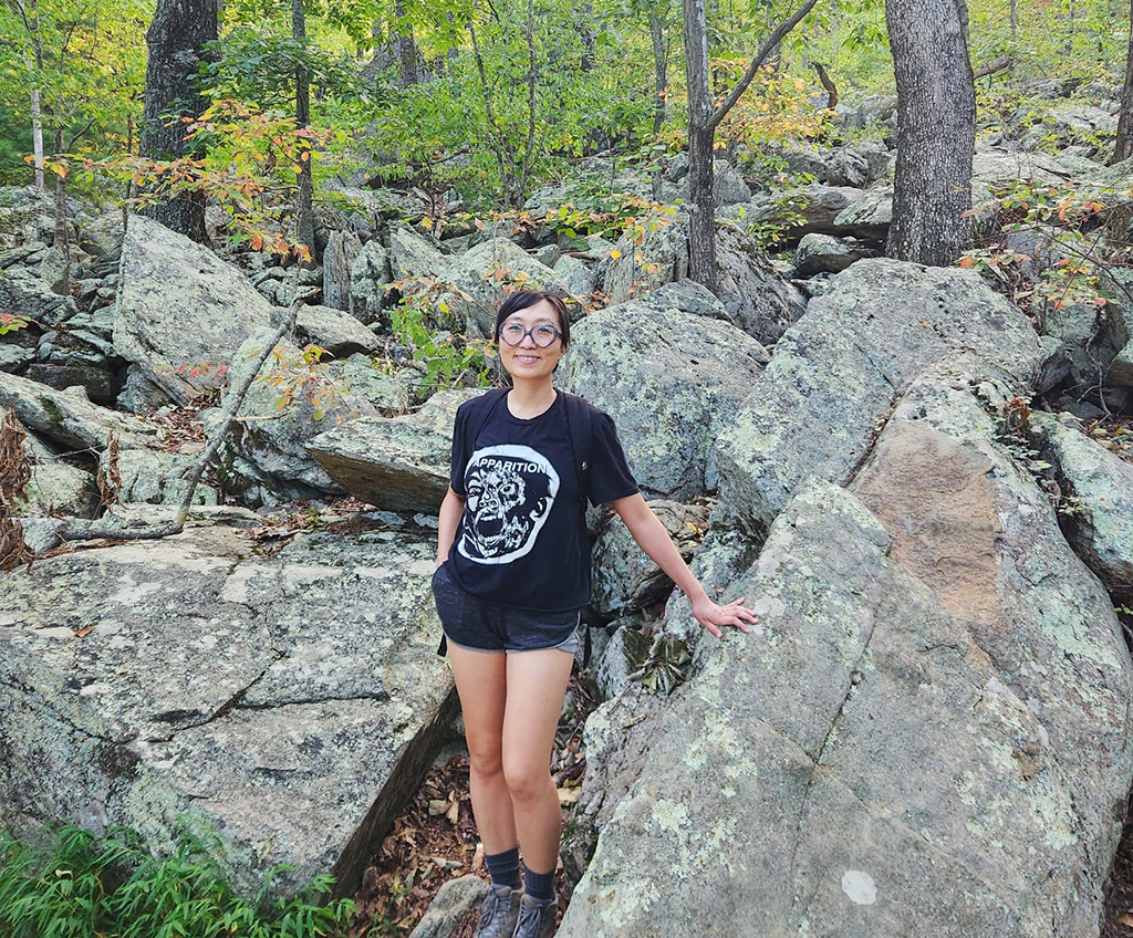 woman standing with big rocks on trail