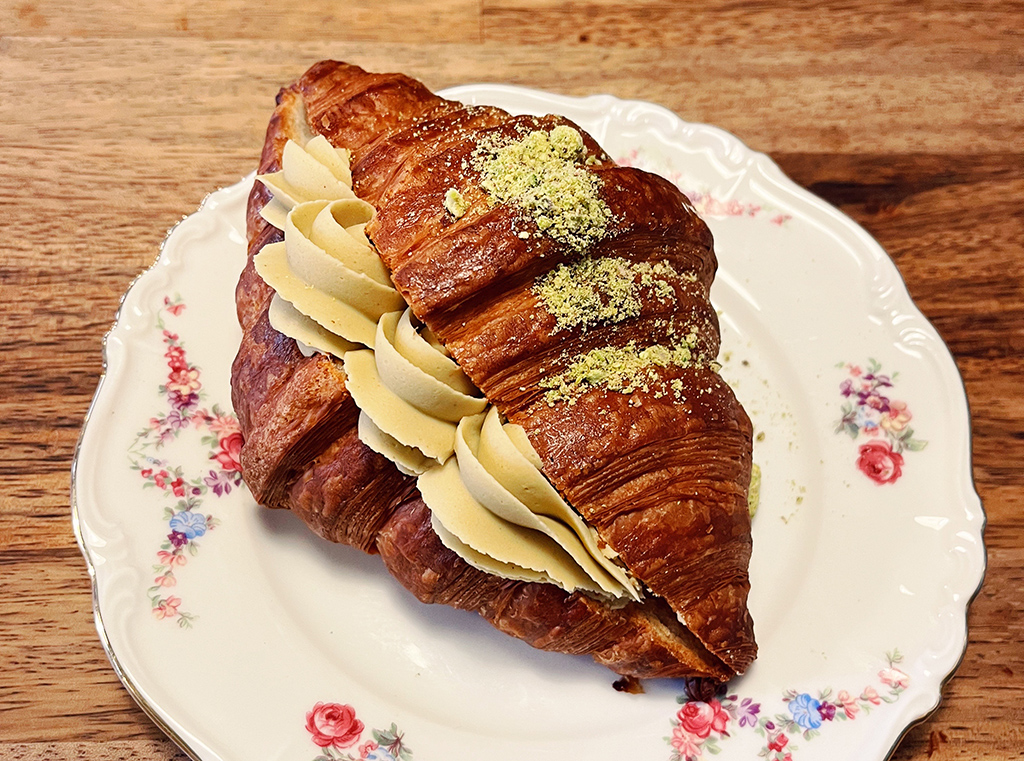 pistachio croissant on a scalloped saucer