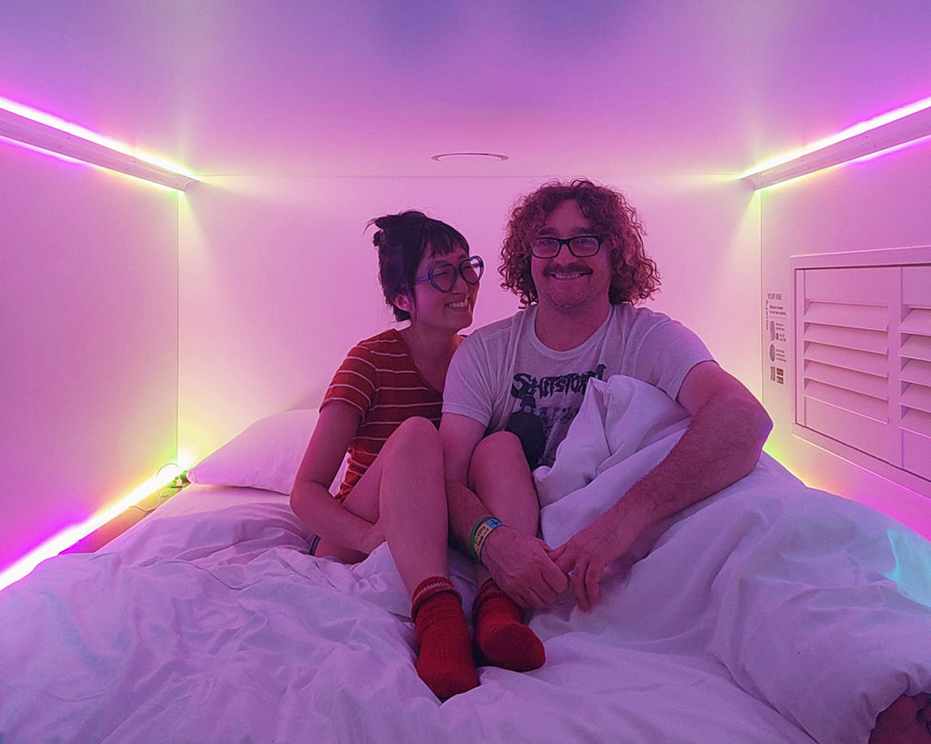 couple in a pink lit capsule hotel