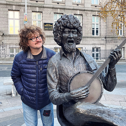 man next to bronze statue