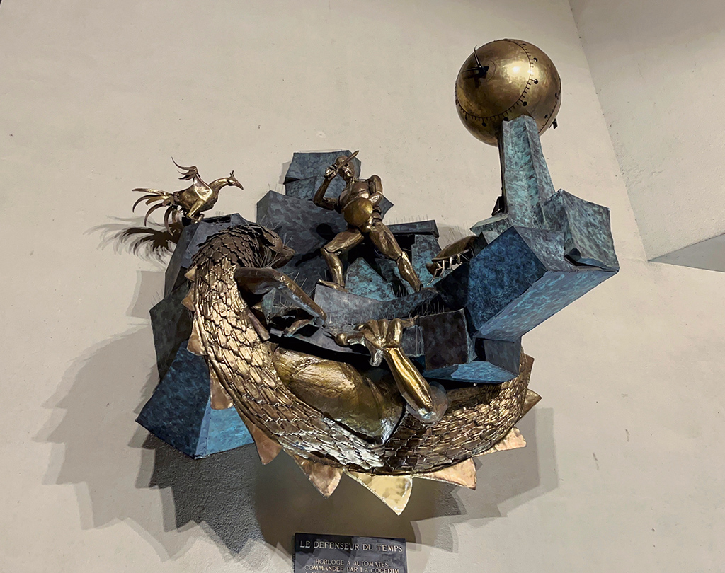 a large brass mechanic sculptural clock with a bird, a dragon, a knight, and a crab