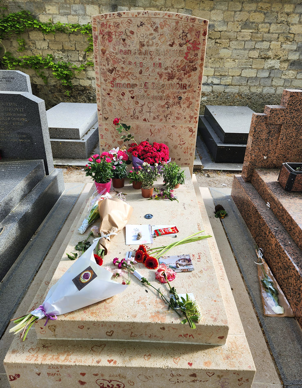 grave of Sartre and Beauvoir, covered in lipstick kisses, flowers and notes