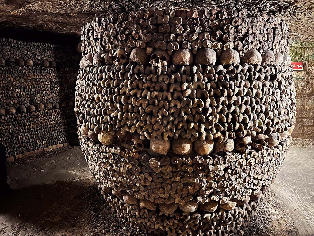 a large found column of bones with rows of skulls in the paris catacombs