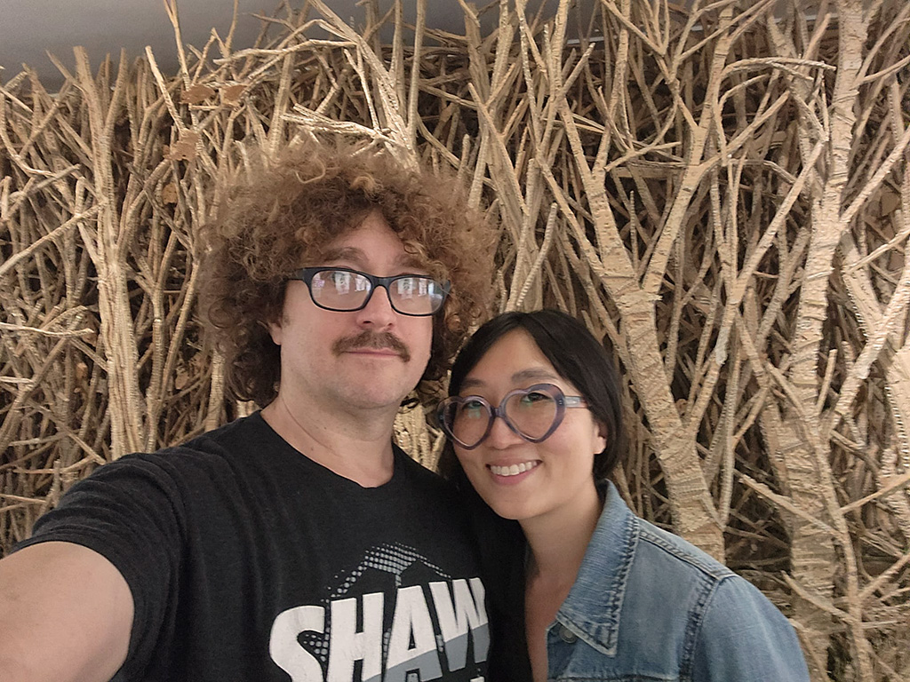 a couple taking a selfie in front of cardboard trees