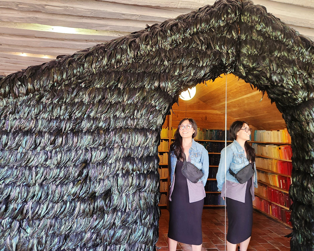 a house covered in black feathers with a woman standing in the open doorway