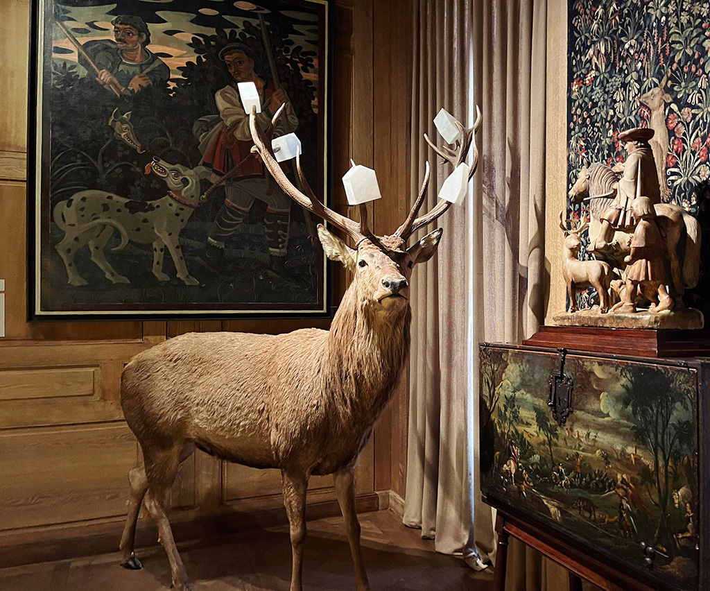 a taxidermy stag with little white houses hanging from his antlers