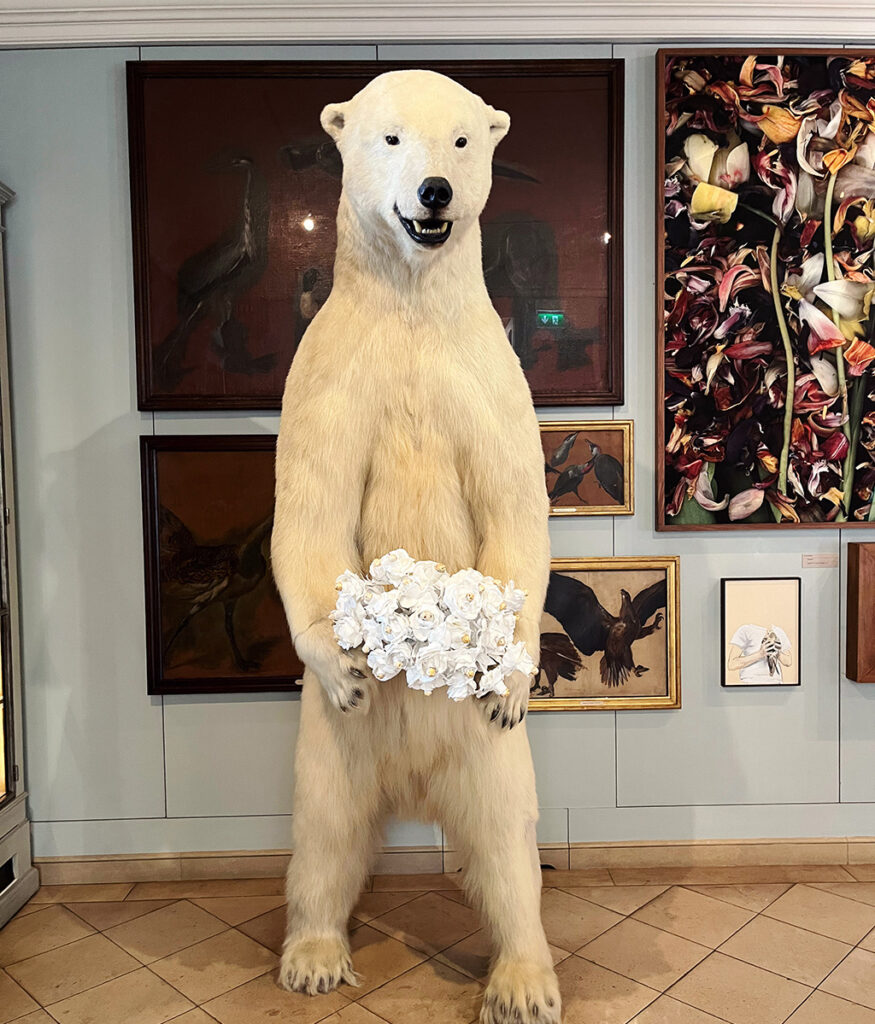 a taxidermy polar bear holding white roses