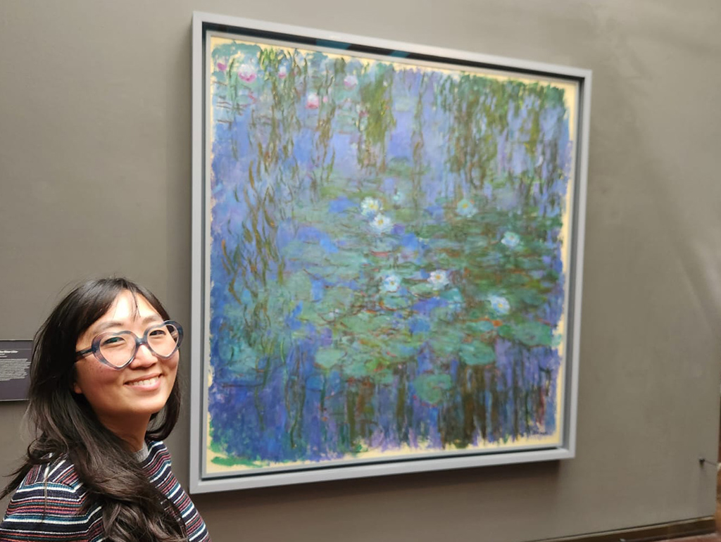 woman smiling by painting of water lilies