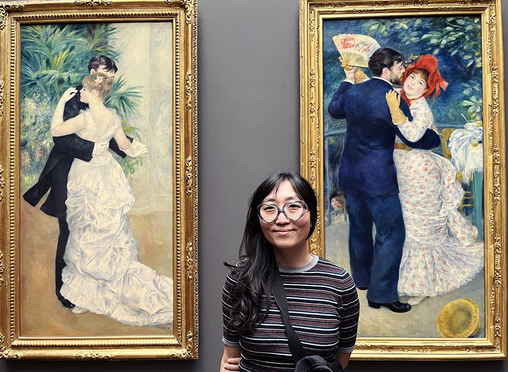 woman standing in between two Renoir paintings of couples dancing