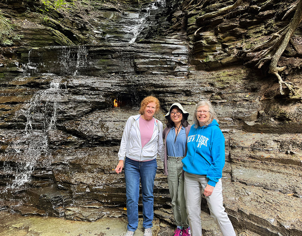 three women posing next to the Eternal Flame Falls