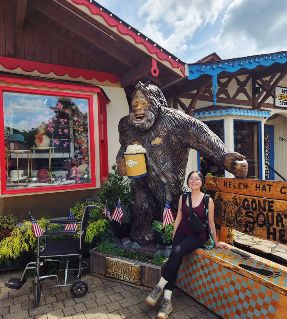 woman sitting next to a statue of sasquatch in a bavarian themed town